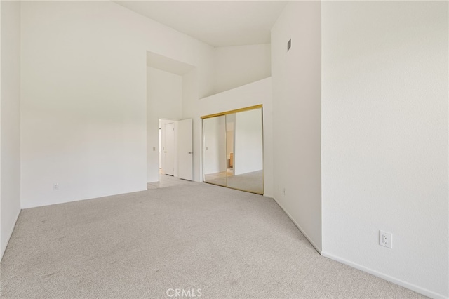 unfurnished room with light carpet and a towering ceiling