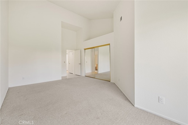 spare room featuring light carpet and a towering ceiling