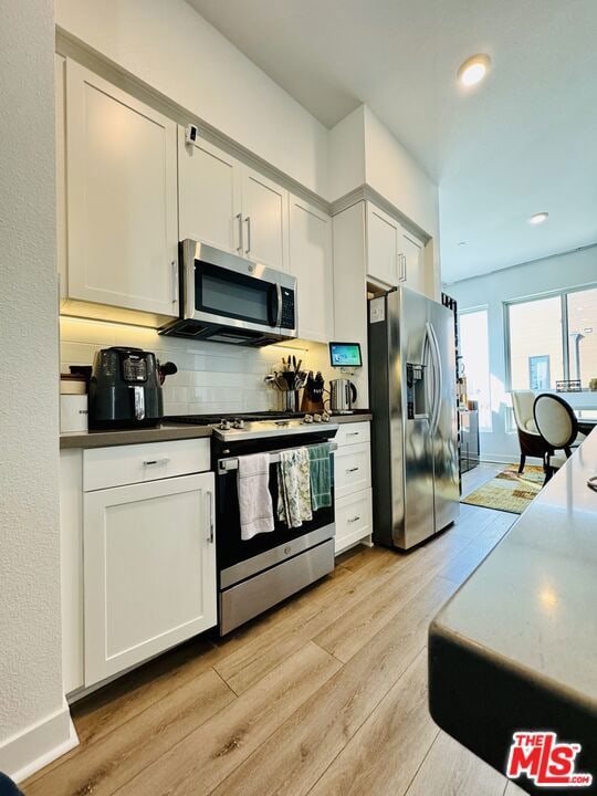 kitchen featuring white cabinets, stainless steel appliances, and light hardwood / wood-style flooring