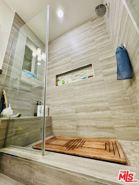 bathroom with a shower and tile walls