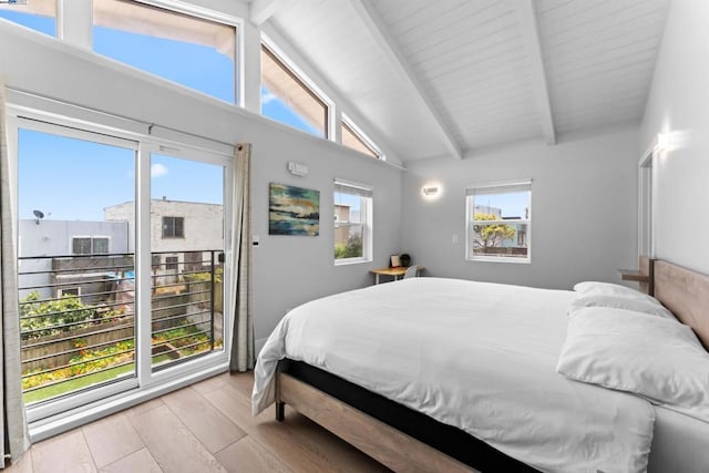 bedroom with multiple windows, light hardwood / wood-style floors, and vaulted ceiling with beams