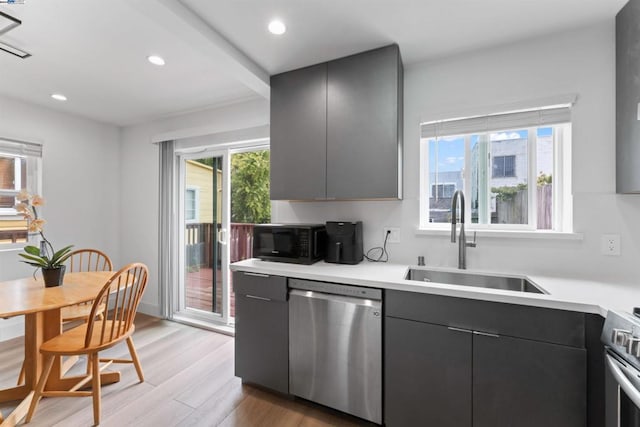 kitchen featuring gray cabinetry, sink, stainless steel appliances, beamed ceiling, and light wood-type flooring