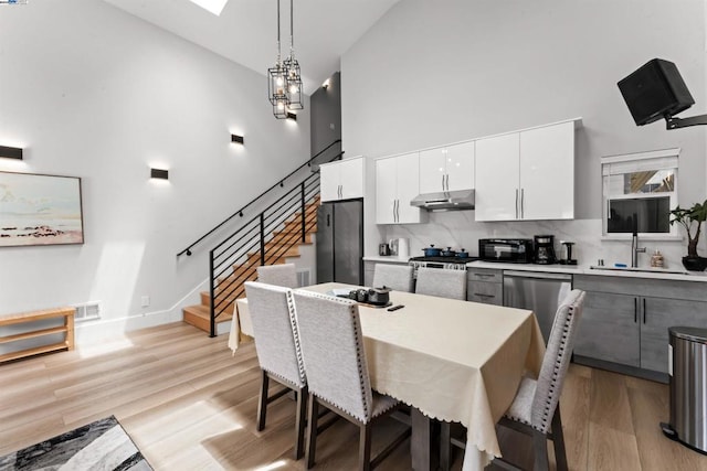 dining room with sink, high vaulted ceiling, light hardwood / wood-style floors, and a notable chandelier