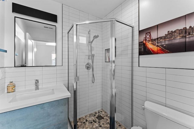 bathroom featuring toilet, a shower with shower door, and tile walls