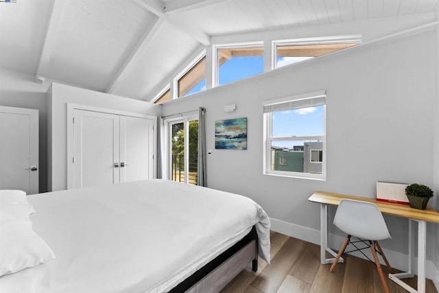 bedroom featuring vaulted ceiling with beams, hardwood / wood-style floors, and access to exterior