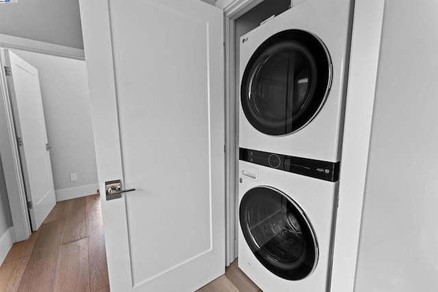 laundry room with stacked washer and dryer and light wood-type flooring