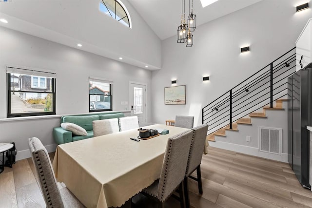 dining area featuring plenty of natural light, high vaulted ceiling, and light hardwood / wood-style flooring