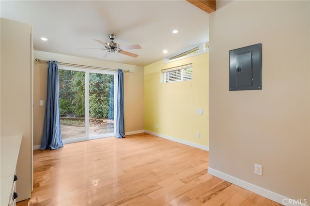 empty room with vaulted ceiling, ceiling fan, electric panel, and light wood-type flooring