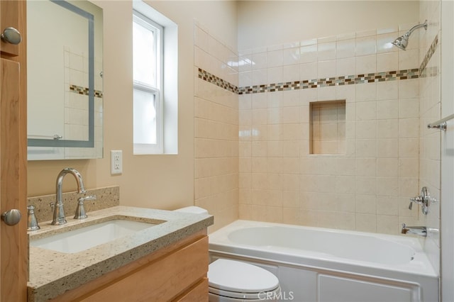 full bathroom featuring tiled shower / bath, vanity, and toilet