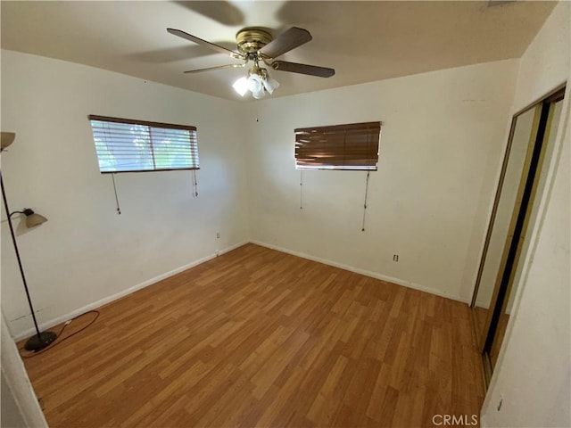 empty room with ceiling fan and light hardwood / wood-style flooring