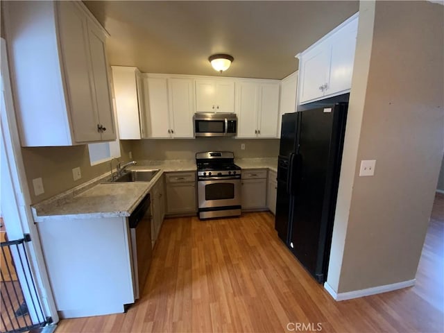 kitchen featuring stainless steel appliances, light hardwood / wood-style floors, white cabinets, and sink