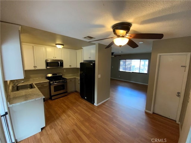 kitchen featuring white cabinetry, stainless steel appliances, sink, light wood-type flooring, and ceiling fan