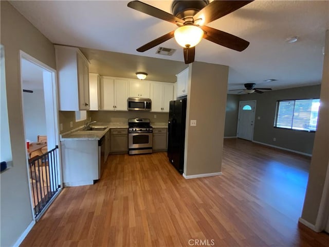 kitchen featuring light wood-type flooring, ceiling fan, appliances with stainless steel finishes, and white cabinetry