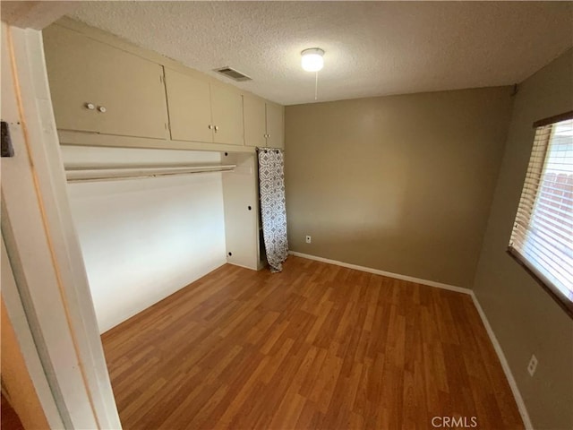 unfurnished bedroom with a closet, a textured ceiling, and hardwood / wood-style flooring