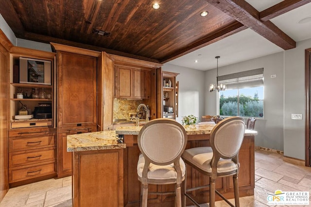 kitchen with pendant lighting, a kitchen bar, backsplash, an inviting chandelier, and light stone counters