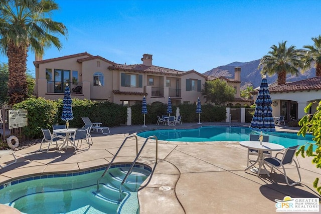 view of pool featuring a mountain view, a patio, and a hot tub