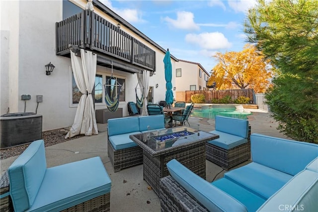 view of patio featuring central AC unit, a fenced in pool, an outdoor living space with a fire pit, a balcony, and a fenced backyard