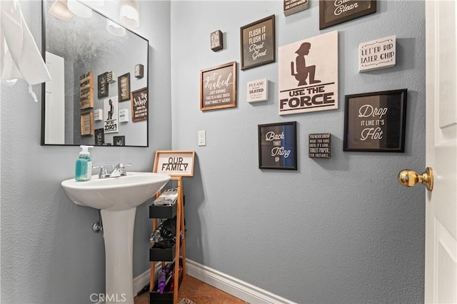 bathroom featuring baseboards and a sink