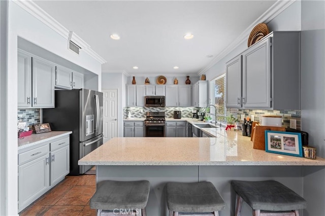 kitchen featuring kitchen peninsula, backsplash, a breakfast bar, stainless steel appliances, and sink