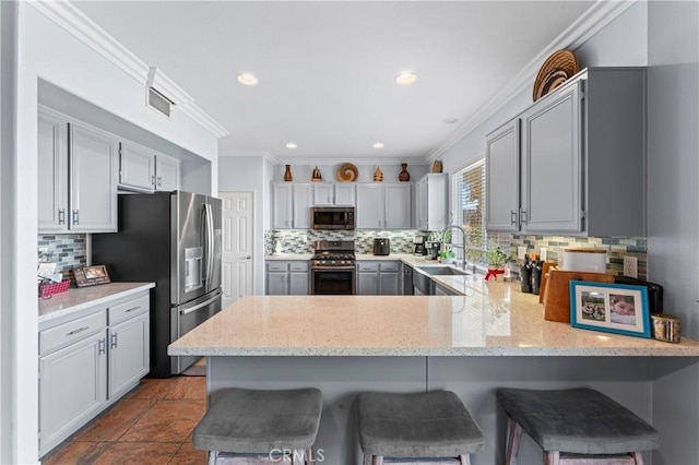 kitchen featuring visible vents, a peninsula, stainless steel appliances, crown molding, and a sink