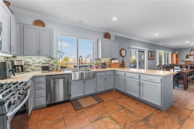 kitchen with appliances with stainless steel finishes, gray cabinets, tasteful backsplash, and sink