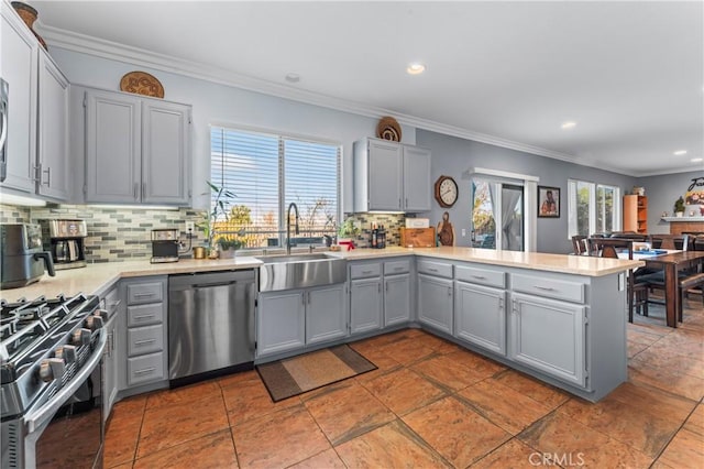 kitchen with stainless steel appliances, a peninsula, a sink, a healthy amount of sunlight, and gray cabinets