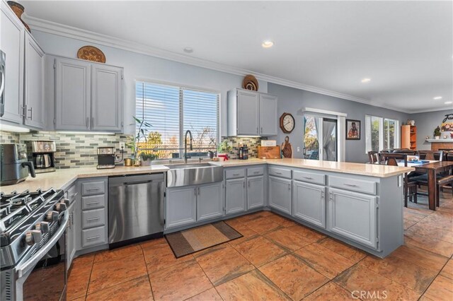 kitchen featuring a sink, stainless steel appliances, light countertops, a peninsula, and gray cabinets