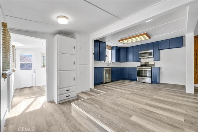 kitchen with sink, blue cabinetry, appliances with stainless steel finishes, and light hardwood / wood-style flooring