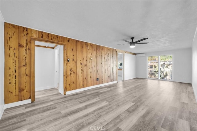 unfurnished living room with wooden walls, light hardwood / wood-style flooring, and ceiling fan