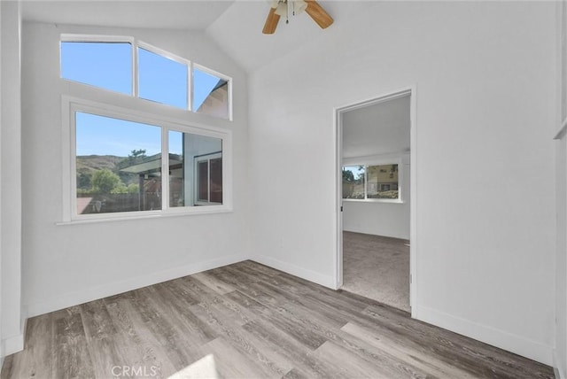 empty room featuring light hardwood / wood-style floors, vaulted ceiling, and ceiling fan