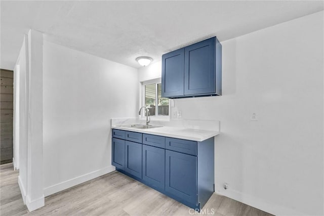 kitchen with blue cabinetry, sink, and light hardwood / wood-style flooring