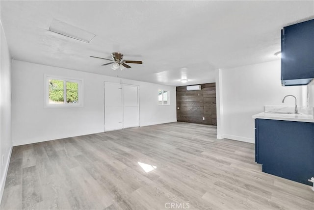 unfurnished living room featuring ceiling fan, sink, and light wood-type flooring