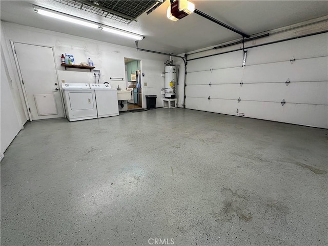 garage featuring washing machine and dryer, water heater, sink, and a garage door opener