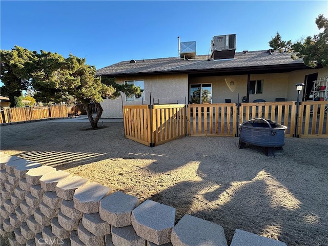 rear view of house featuring cooling unit and a fire pit