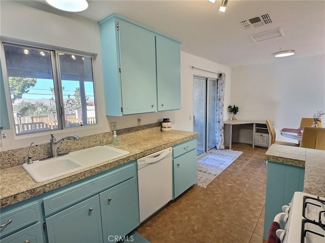 kitchen featuring white dishwasher, stove, dark tile patterned floors, and sink