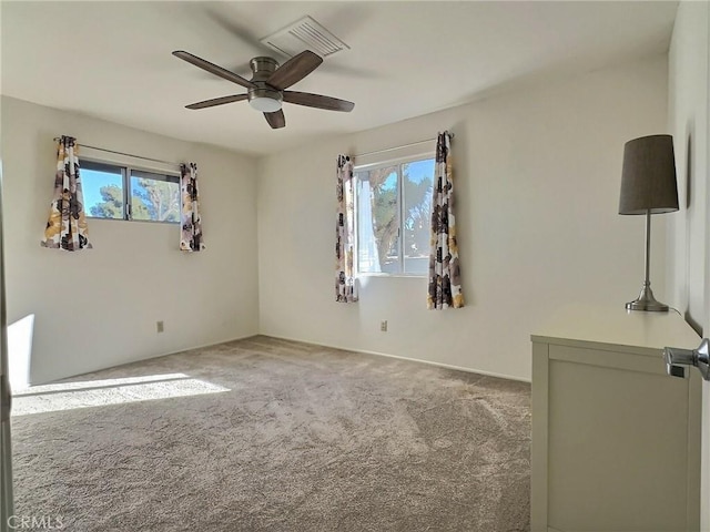 carpeted spare room with ceiling fan and plenty of natural light