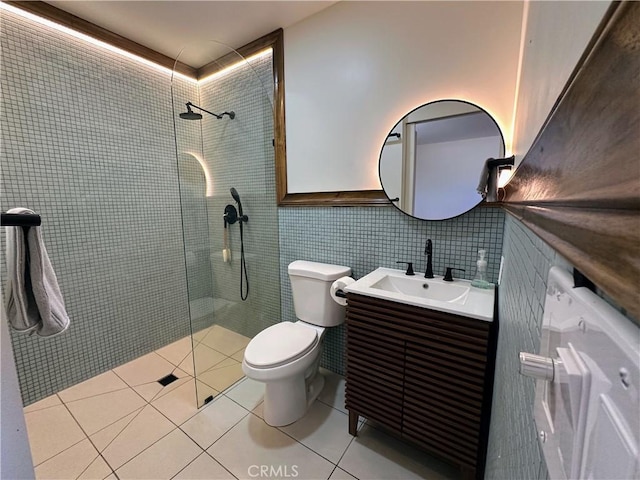 bathroom with tile patterned floors, a tile shower, vanity, tile walls, and toilet