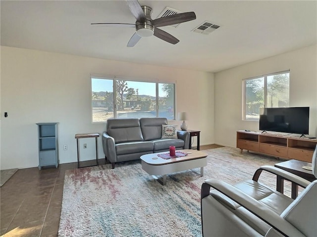 living room with ceiling fan and dark tile patterned floors