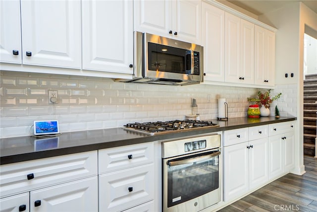 kitchen featuring backsplash, white cabinetry, dark wood-type flooring, and appliances with stainless steel finishes