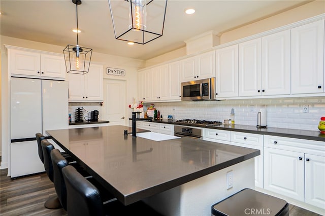 kitchen featuring white cabinetry, dark hardwood / wood-style flooring, decorative light fixtures, and appliances with stainless steel finishes