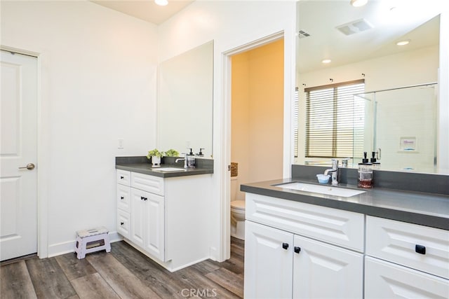 bathroom featuring a shower, wood-type flooring, vanity, and toilet