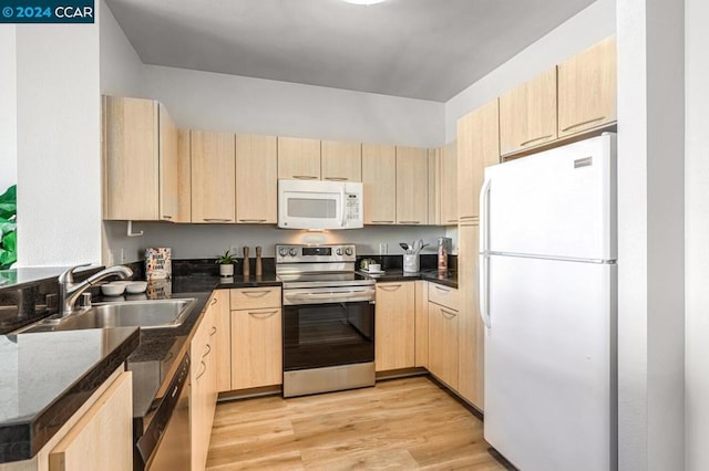 kitchen with sink, light brown cabinets, dark stone counters, light hardwood / wood-style floors, and appliances with stainless steel finishes