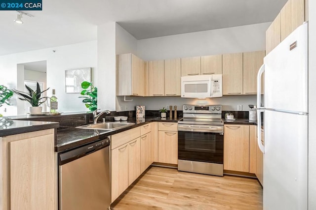 kitchen with sink, light wood-type flooring, light brown cabinets, and appliances with stainless steel finishes