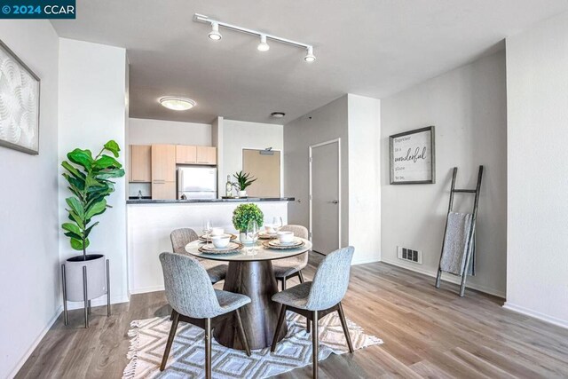 dining space with light wood-type flooring and rail lighting