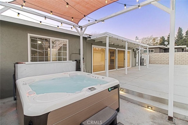 patio terrace at dusk featuring a hot tub