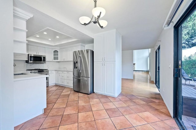 kitchen with light tile patterned flooring, white cabinetry, decorative light fixtures, a raised ceiling, and stainless steel appliances