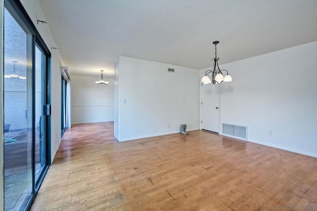 unfurnished room featuring a chandelier and light hardwood / wood-style flooring