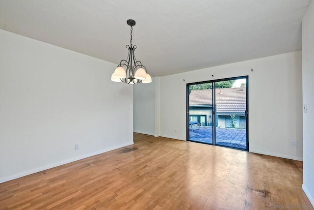 empty room with a chandelier and light hardwood / wood-style floors