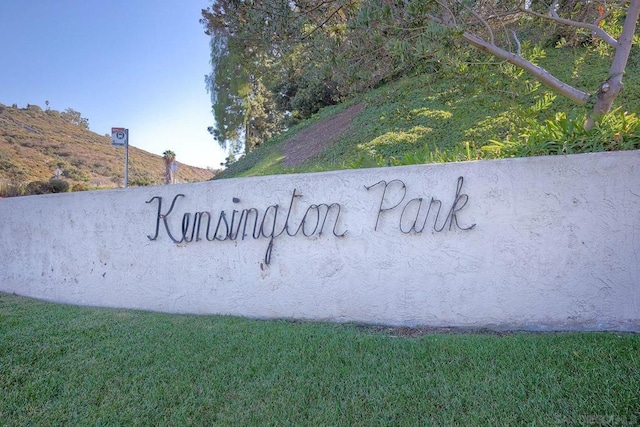 community / neighborhood sign featuring a mountain view and a yard