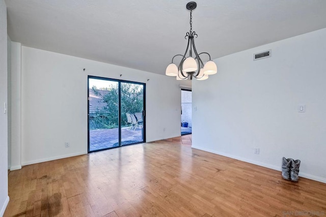 unfurnished room featuring hardwood / wood-style floors and a notable chandelier